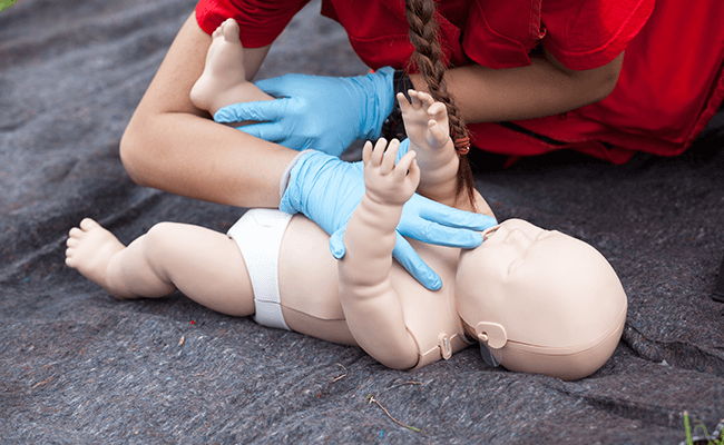 First Aid Trainer Showing how to give a Baby CPR in a First Aid and CPR Training course for mums and educators