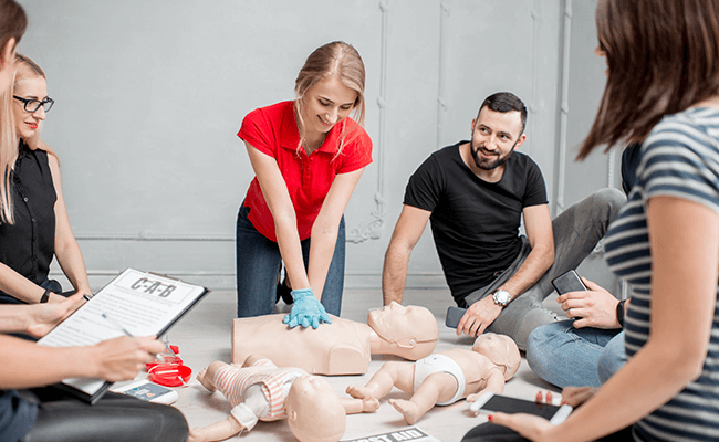 Class learning how to perform CPR and First Aid in a training course