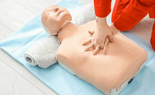 First Aid Trainer showing how to perform CPR Chest Compression on a CPR dummy